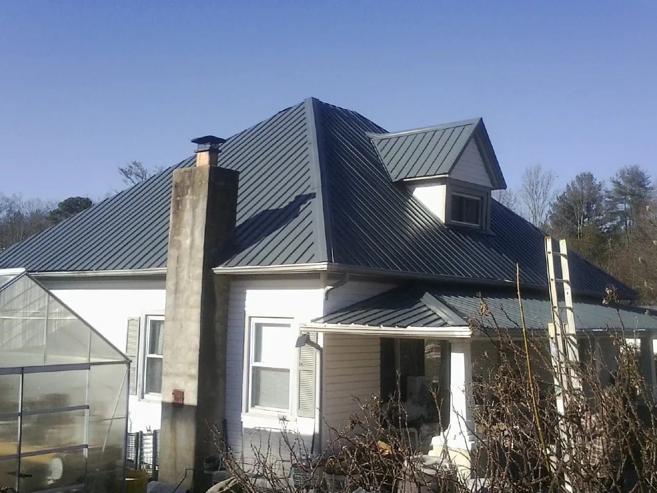Dark blue standing seam metal roof on a white farmhouse with dormer — Slate & Tile Roof Repair by Roofing Brothers in Flintstone