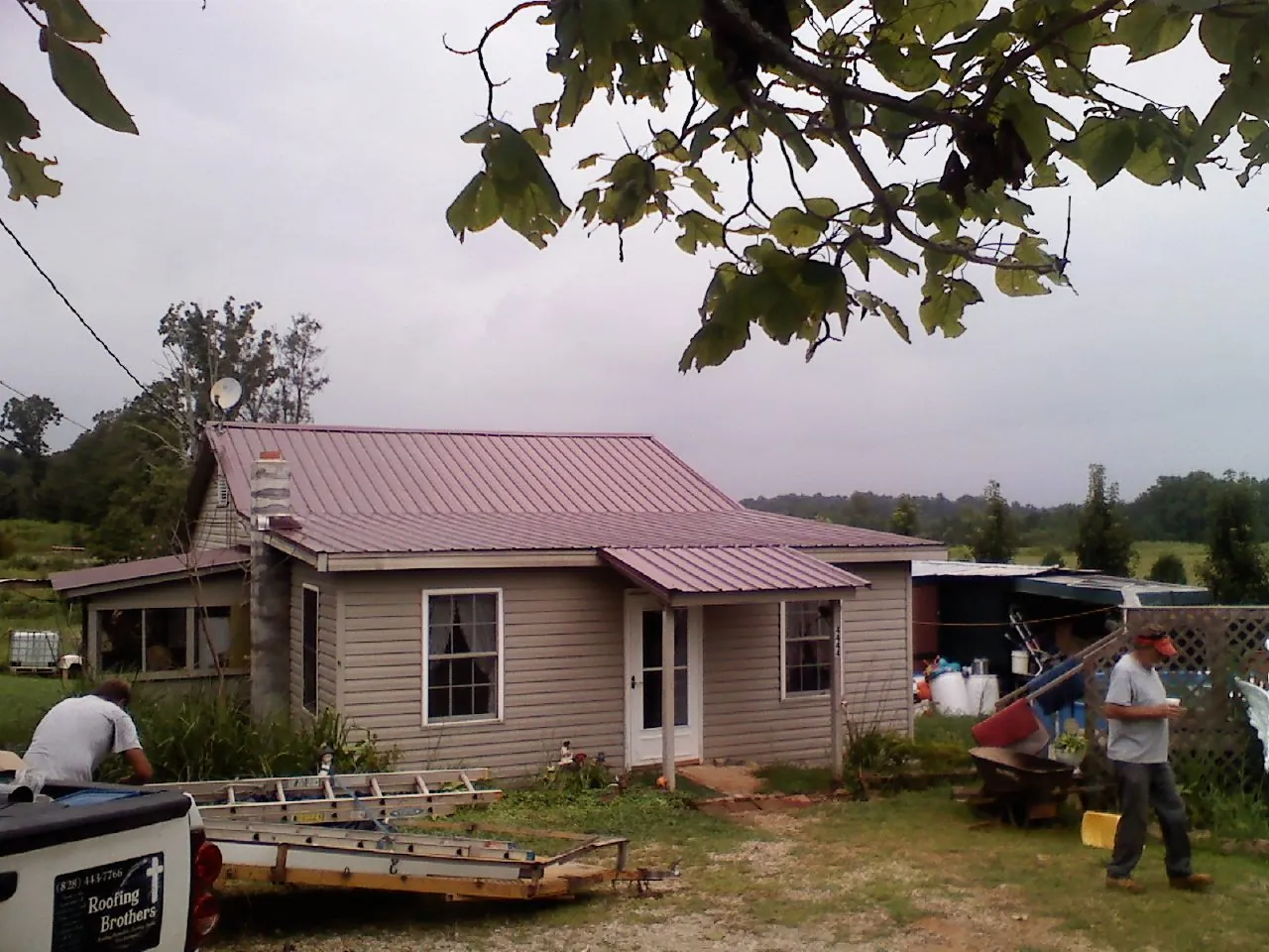 Crew finishing a mauve metal roof on a small farmhouse in Flintstone